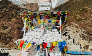Trekker standing beside a Buddhist stupa with Mount Manaslu in the background.