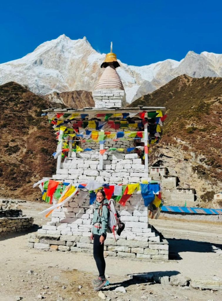 Trekker standing beside a Buddhist stupa with Mount Manaslu in the background.