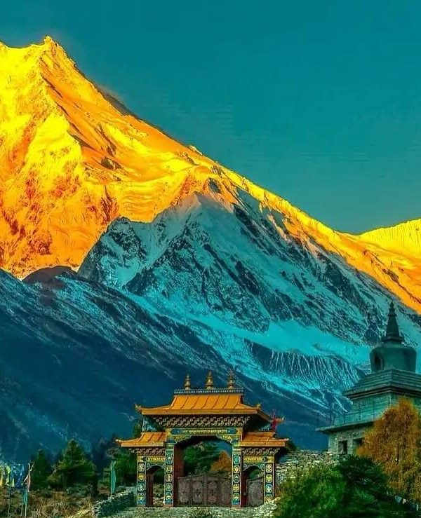 Golden sunrise over Mount Manaslu with a Buddhist monastery gate in the foreground, captured during the Manaslu Circuit Trek in Nepal.