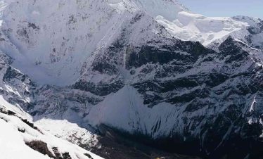 Trekker climbing snowy slopes with Manaslu mountain towering above.