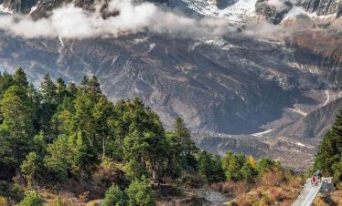 Suspension bridge on the Manaslu Circuit Trek with snow-capped mountains in the background.