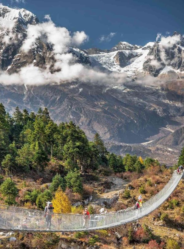 Suspension bridge on the Manaslu Circuit Trek with snow-capped mountains in the background.