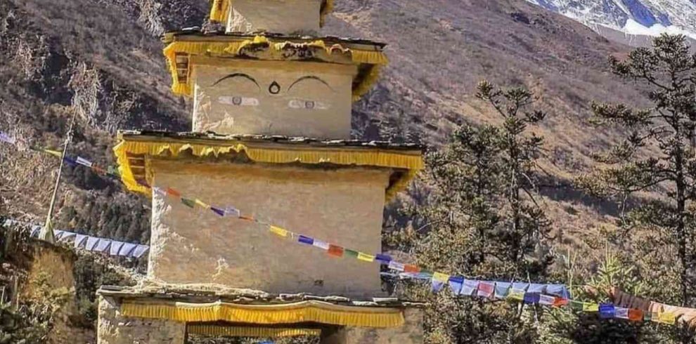 Trekkers walking through a traditional Buddhist gate with Mount Manaslu in the background.