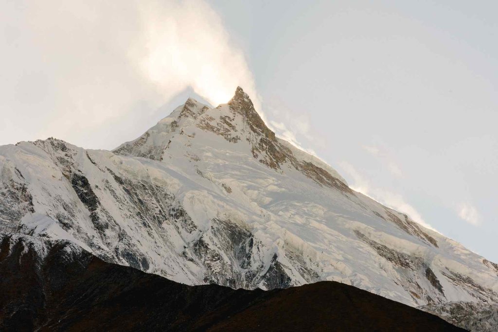 Snow-capped Mount Manaslu peak glowing at sunrise in the Himalayas, Nepal.