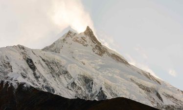 Snow-capped Mount Manaslu peak glowing at sunrise in the Himalayas, Nepal.