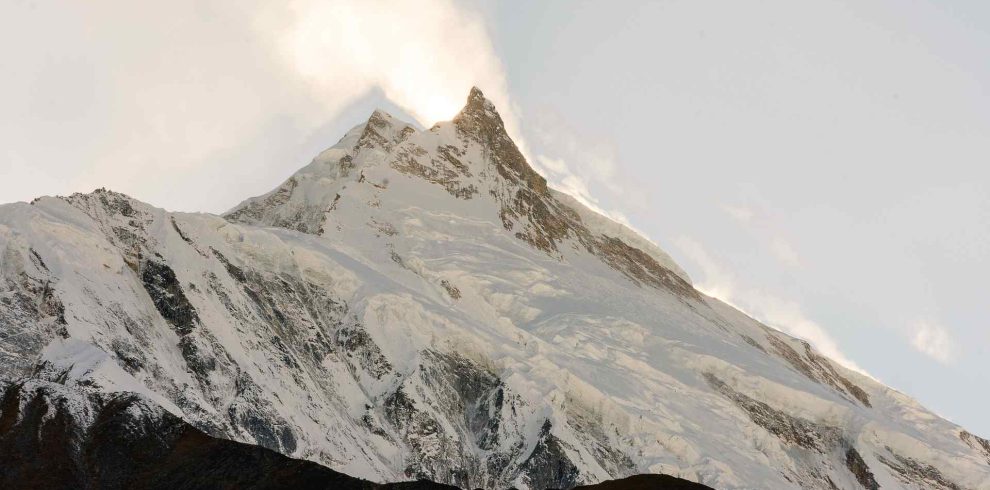 Snow-capped Mount Manaslu peak glowing at sunrise in the Himalayas, Nepal.