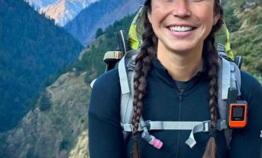 Trekker posing under the colorful Tsum Valley welcome gate in Nepal.