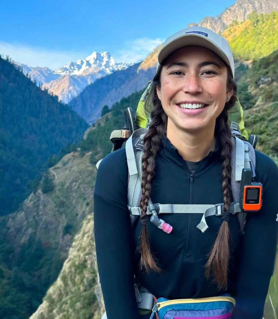 Trekker posing under the colorful Tsum Valley welcome gate in Nepal.
