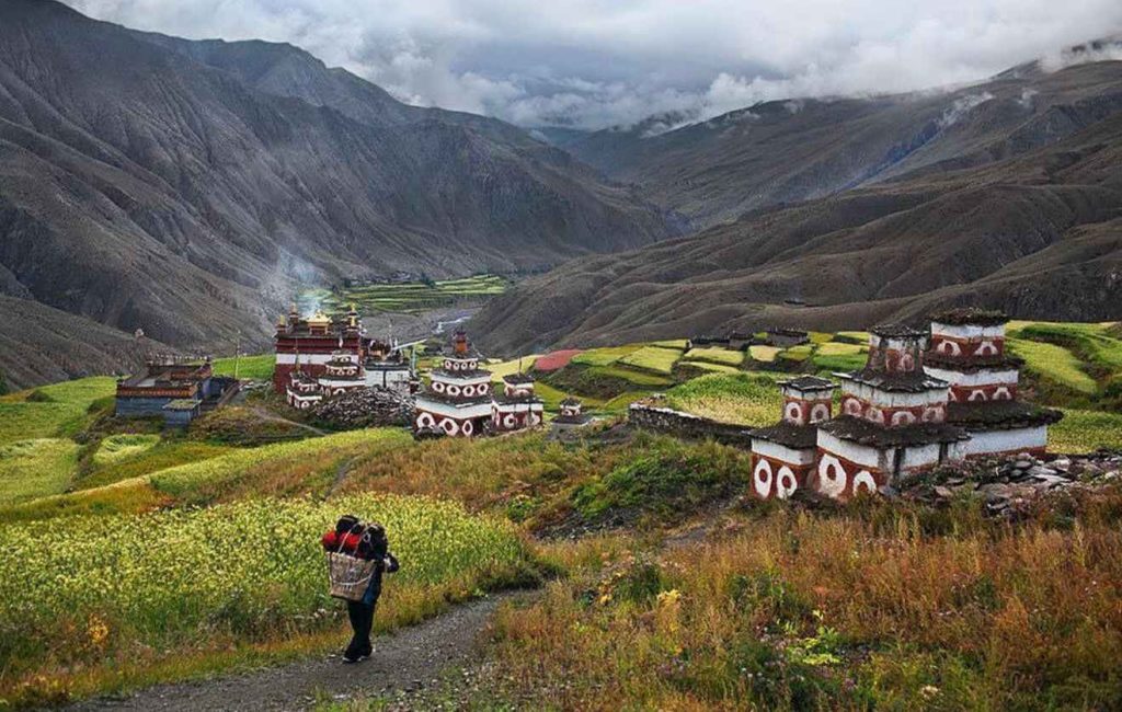 Chortens and traditional houses in Tsum Valley surrounded by terraced fields and dramatic
