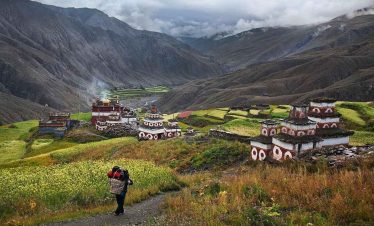 Chortens and traditional houses in Tsum Valley surrounded by terraced fields and dramatic