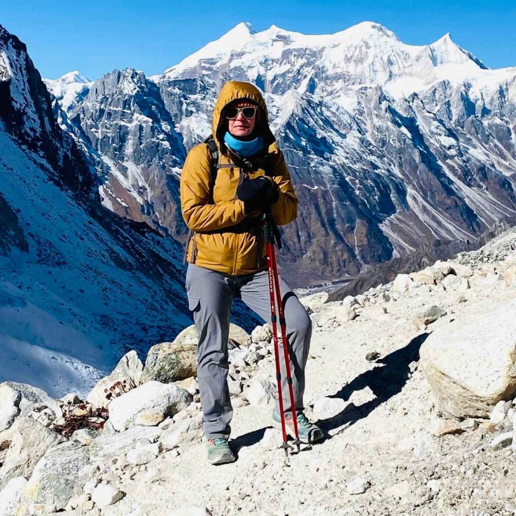 Solo trekker standing on the Manaslu Circuit trail with snow-covered mountains in the background in Nepal.