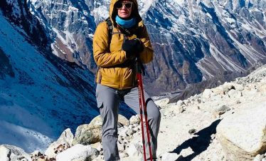 Solo trekker standing on the Manaslu Circuit trail with snow-covered mountains in the background in Nepal.
