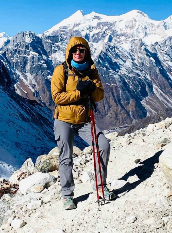 Solo trekker standing on the Manaslu Circuit trail with snow-covered mountains in the background in Nepal.