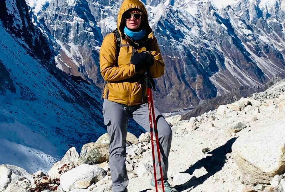 Solo trekker standing on the Manaslu Circuit trail with snow-covered mountains in the background in Nepal.