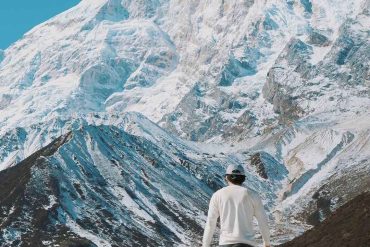 Trekker walking toward Mount Manaslu snow covered peaks on Manaslu Circuit trek Nepal