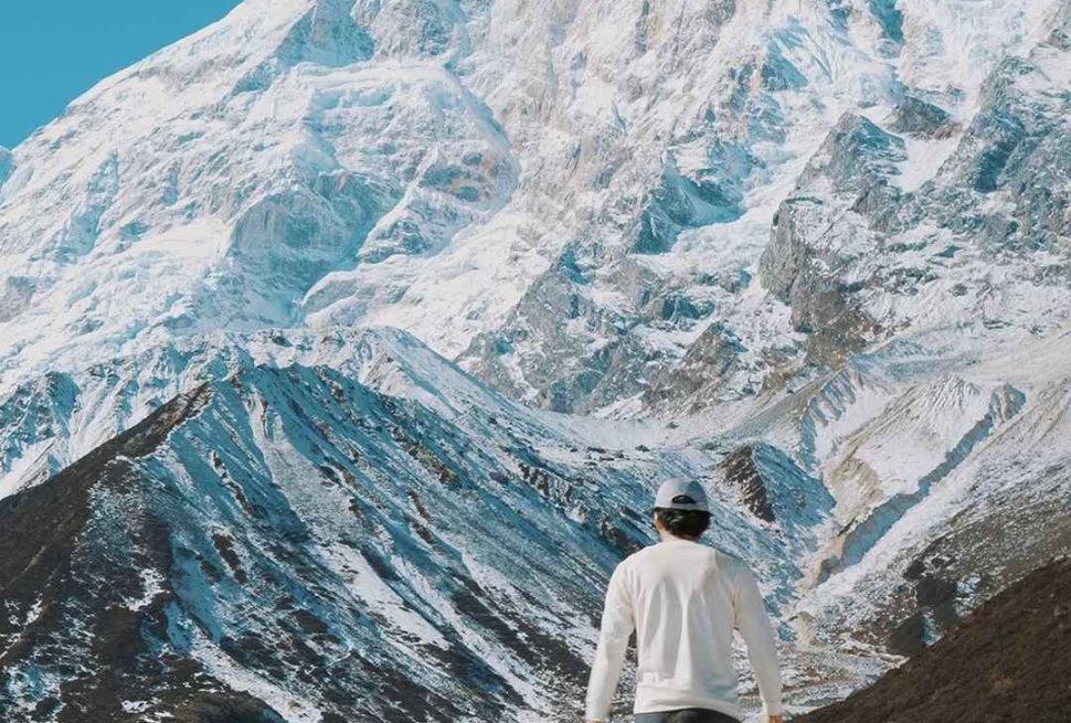 Trekker walking toward Mount Manaslu snow covered peaks on Manaslu Circuit trek Nepal