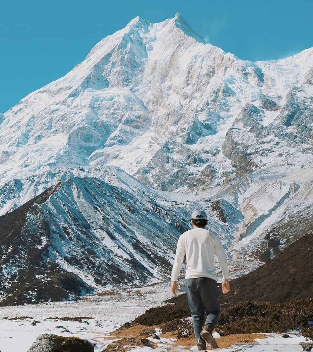 Trekker walking toward Mount Manaslu snow covered peaks on Manaslu Circuit trek Nepal
