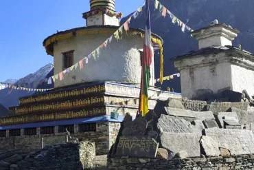 Quiet trail with a whitewashed chorten and prayer flags on the Manaslu Tsum Valley Trek in Nepal