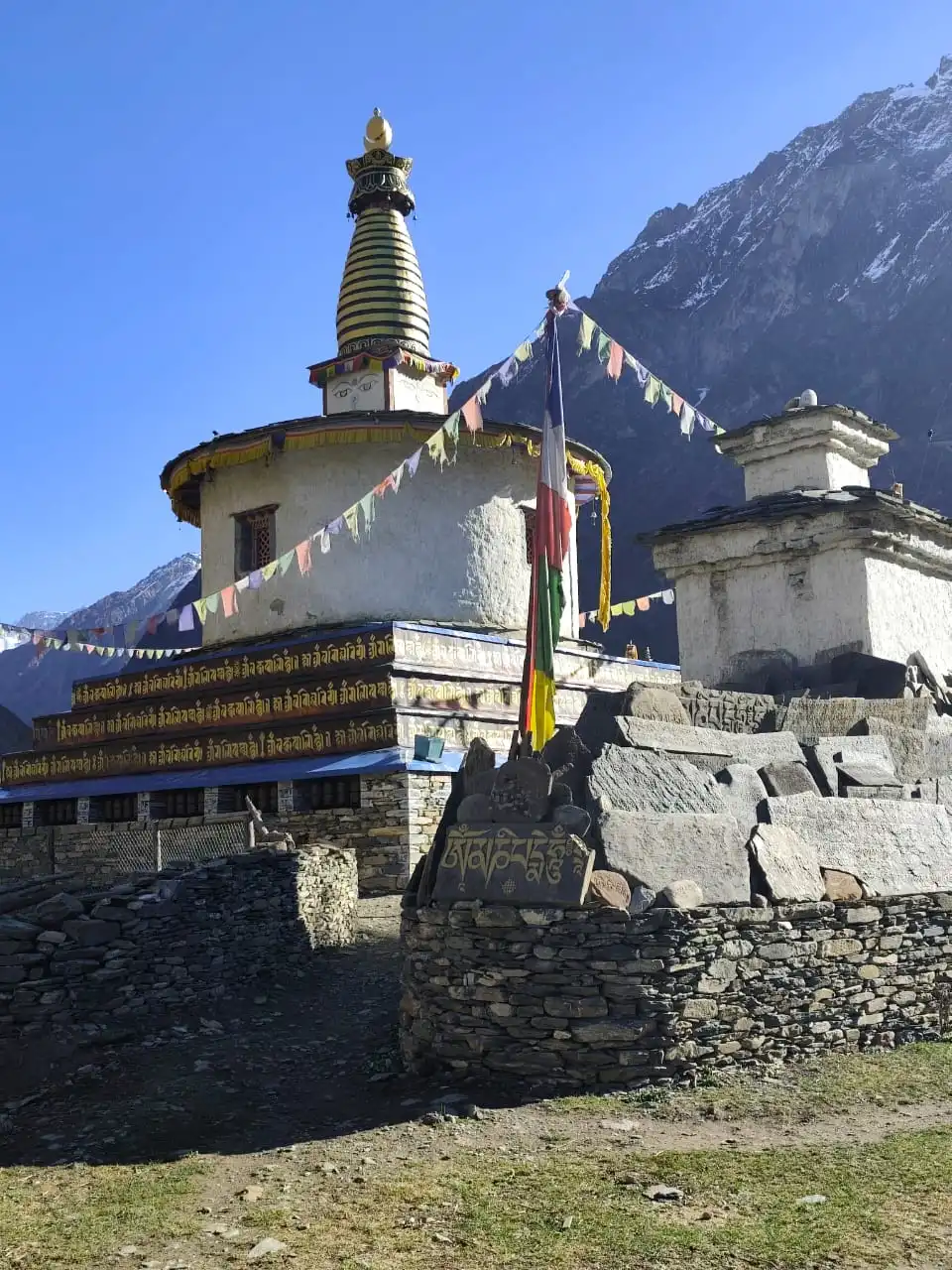 Quiet trail with a whitewashed chorten and prayer flags on the Manaslu Tsum Valley Trek in Nepal